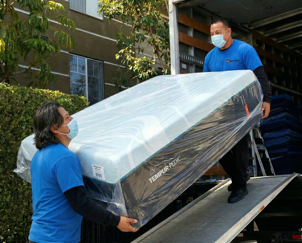 LA Mattress Store delivery crew unloading a wrapped Tempur-Pedic mattress from the delivery truck in Los Angeles