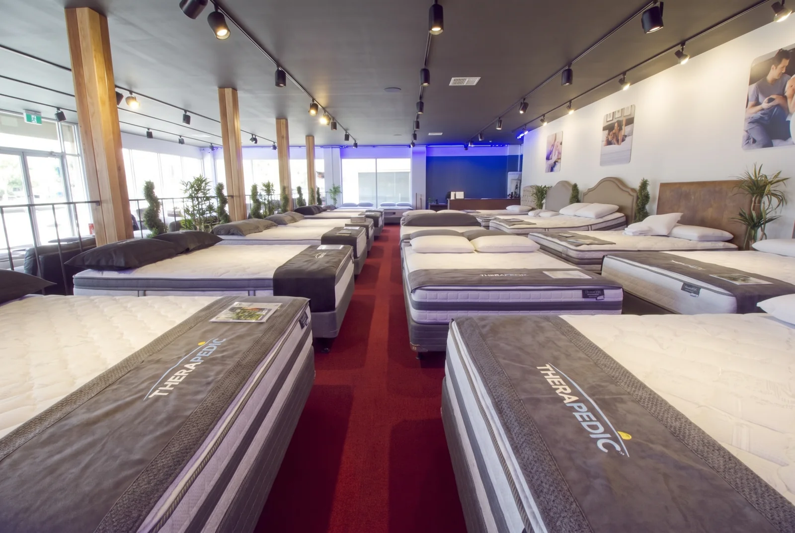 Recreated LA Mattress showroom with red carpet, timber columns and branded display beds