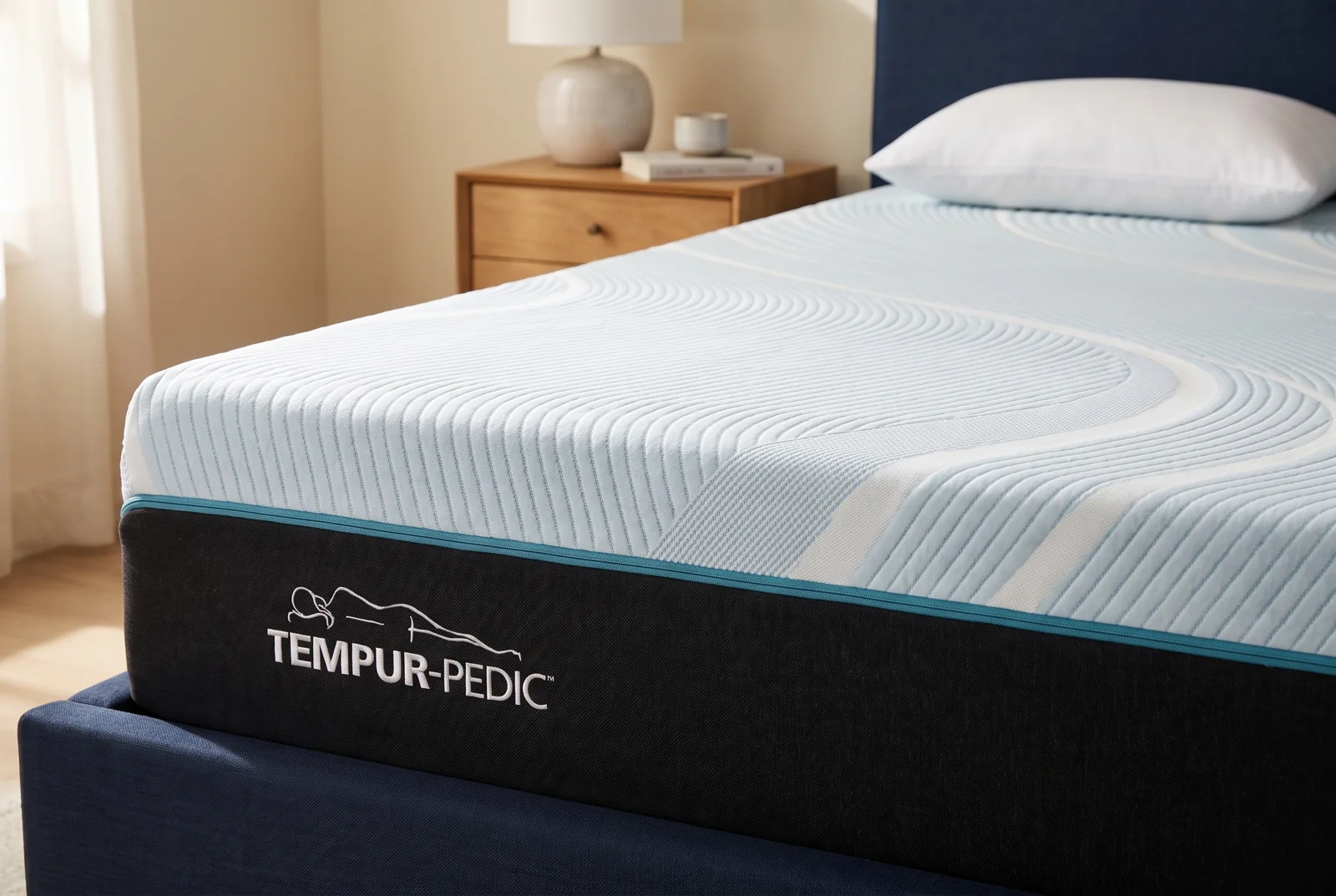 A styled close view of the TEMPUR-ProAdapt cover, turquoise piping and branded sidewall