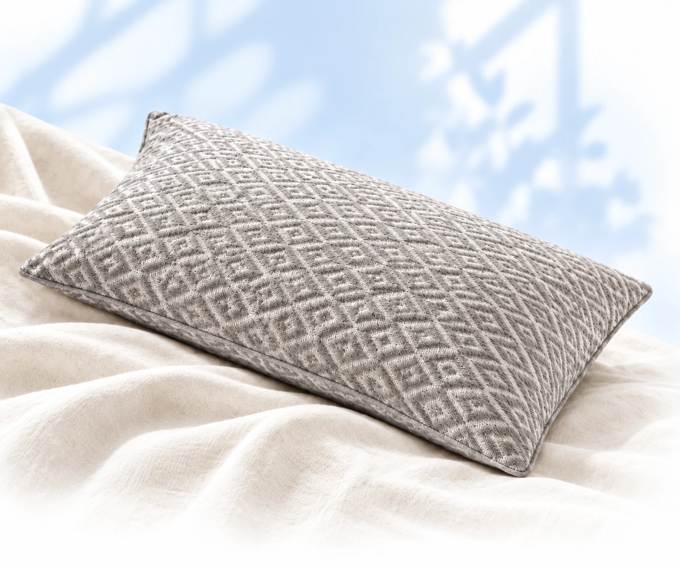 A gray quilted pillow resting on soft linen bedding in morning light