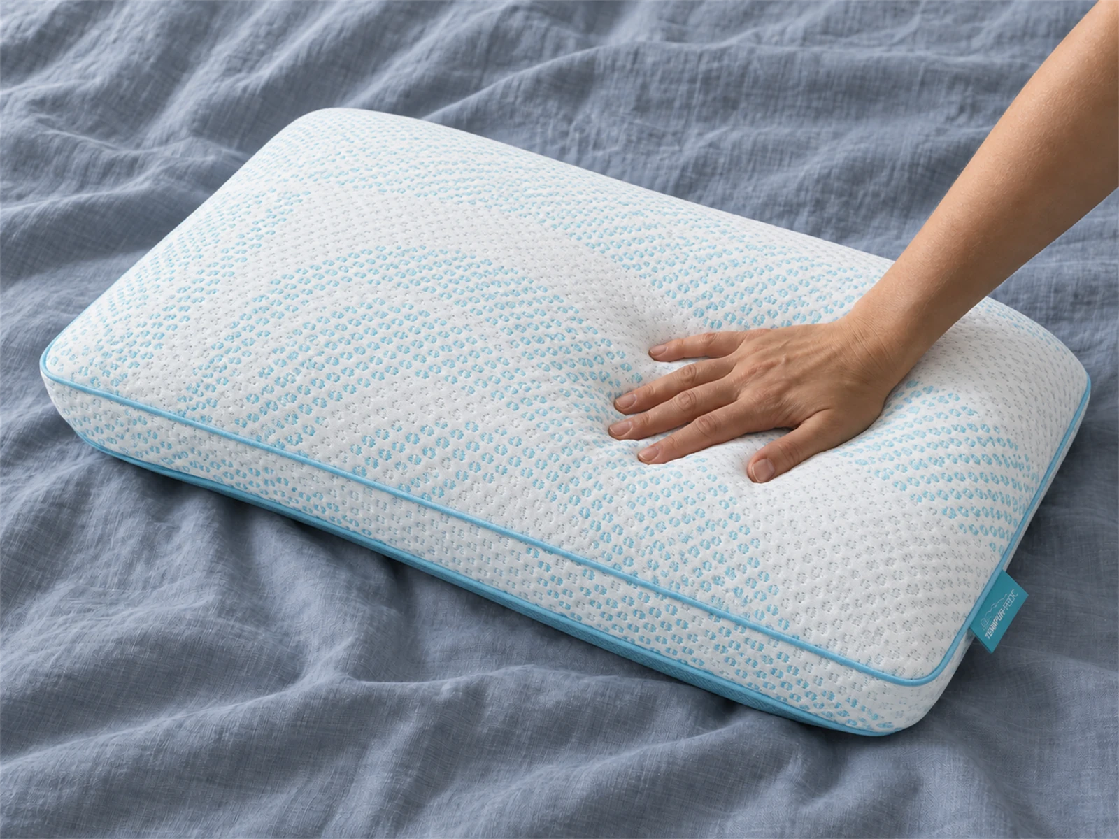 Tempur-Pedic TEMPUR-Breeze Pro + Advanced Cooling Pillow: Hand pressing the pillow on blue-gray linen
