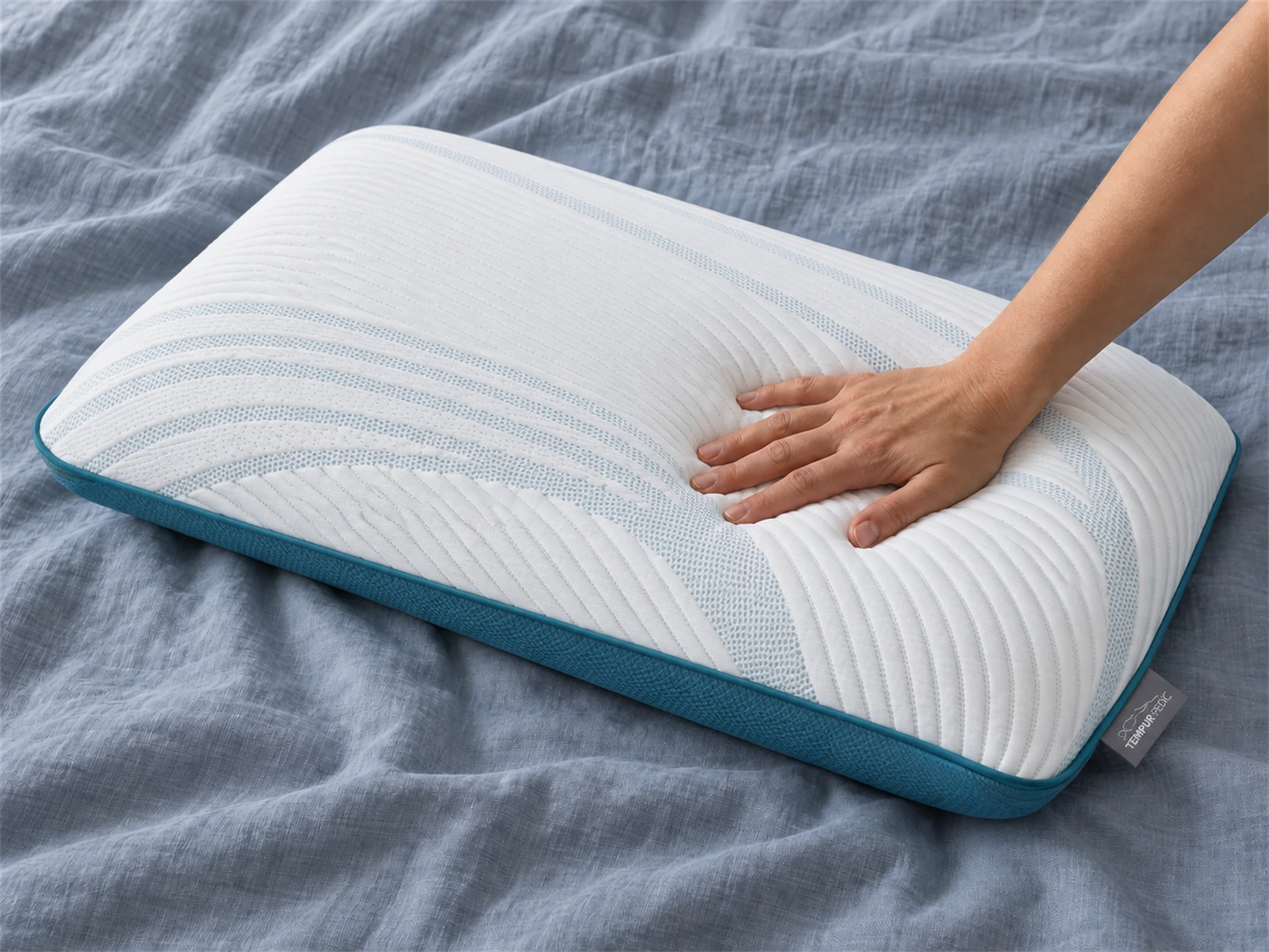 Tempur-Pedic TEMPUR-Cloud Pillow: Hand pressing the pillow on blue-gray linen